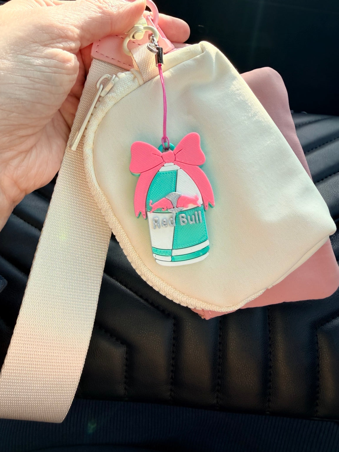 Pink and turquoise Big Bow Energy PopOff keychain clipped to a small cream bag