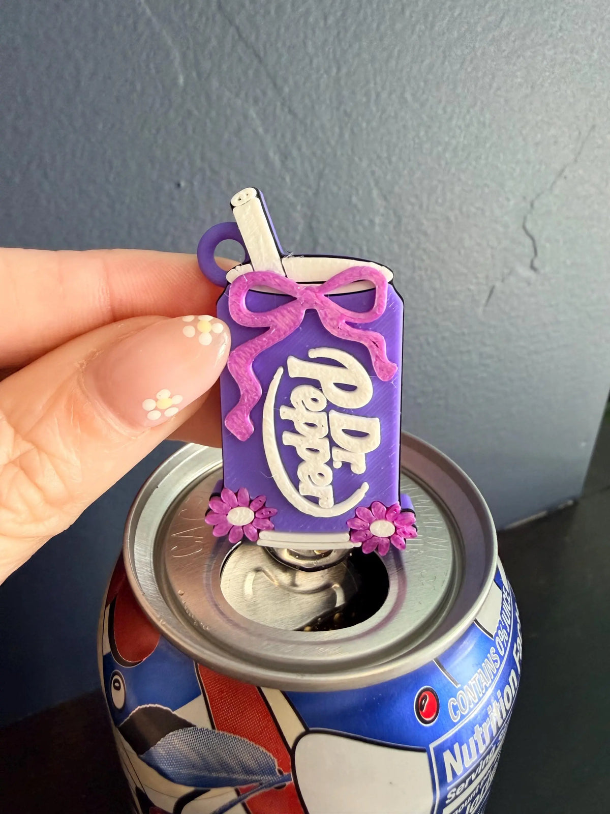 Cherry soda-inspired PopOff can tab opener keychain held with a canned drink