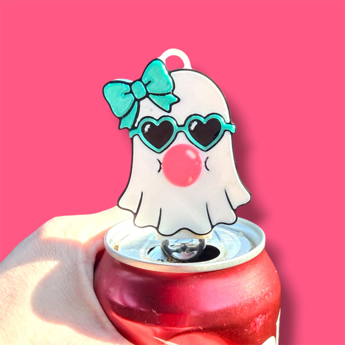 Pocket Magic ghost-themed can tab opener with heart sunglasses, teal bow, and bubblegum on a red soda can
