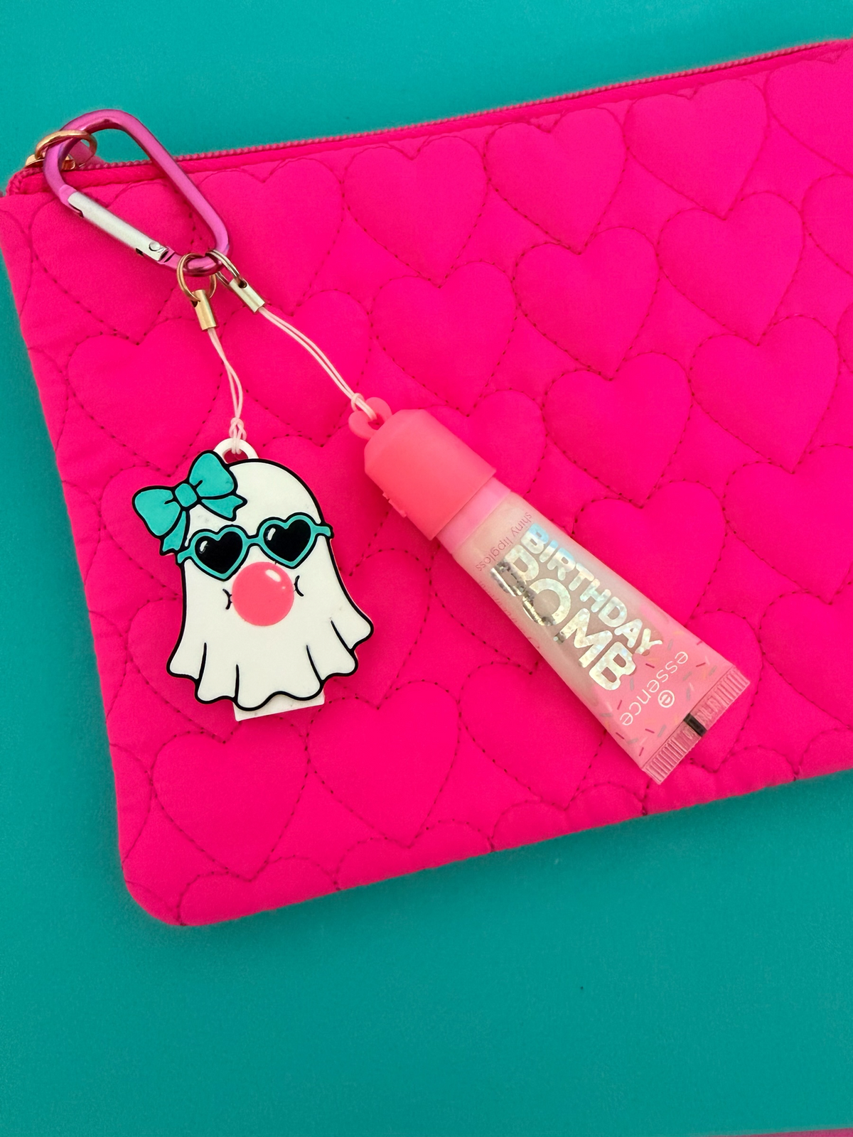 Pocket Magic essence Birthday Bomb lip gloss and cute ghost keychain with bow and sunglasses on a pink heart pouch